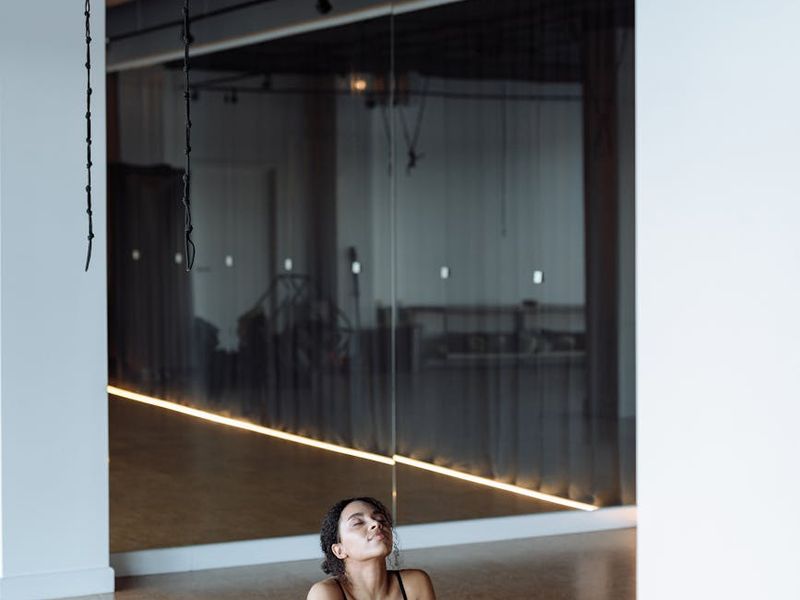 Woman practicing yoga on a mat in a minimalist studio environment.